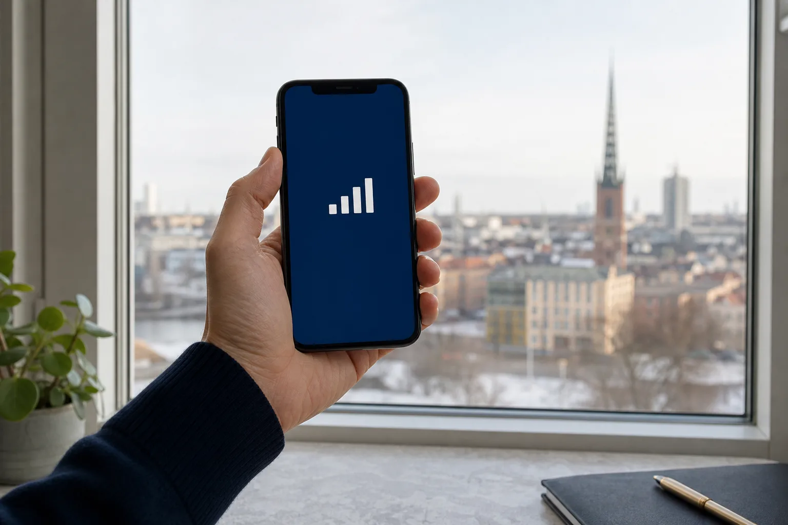 Mobil med signalstreck hålls upp mot ett stadsfönster